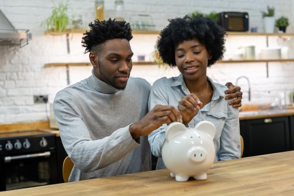 A couple putting coins into a piggy bank.