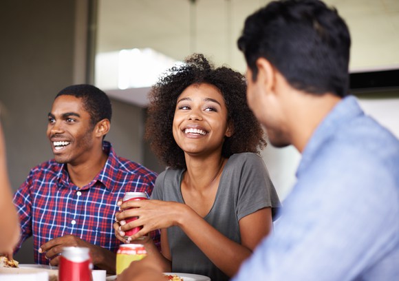 Friends drinking soda while eating pizza.