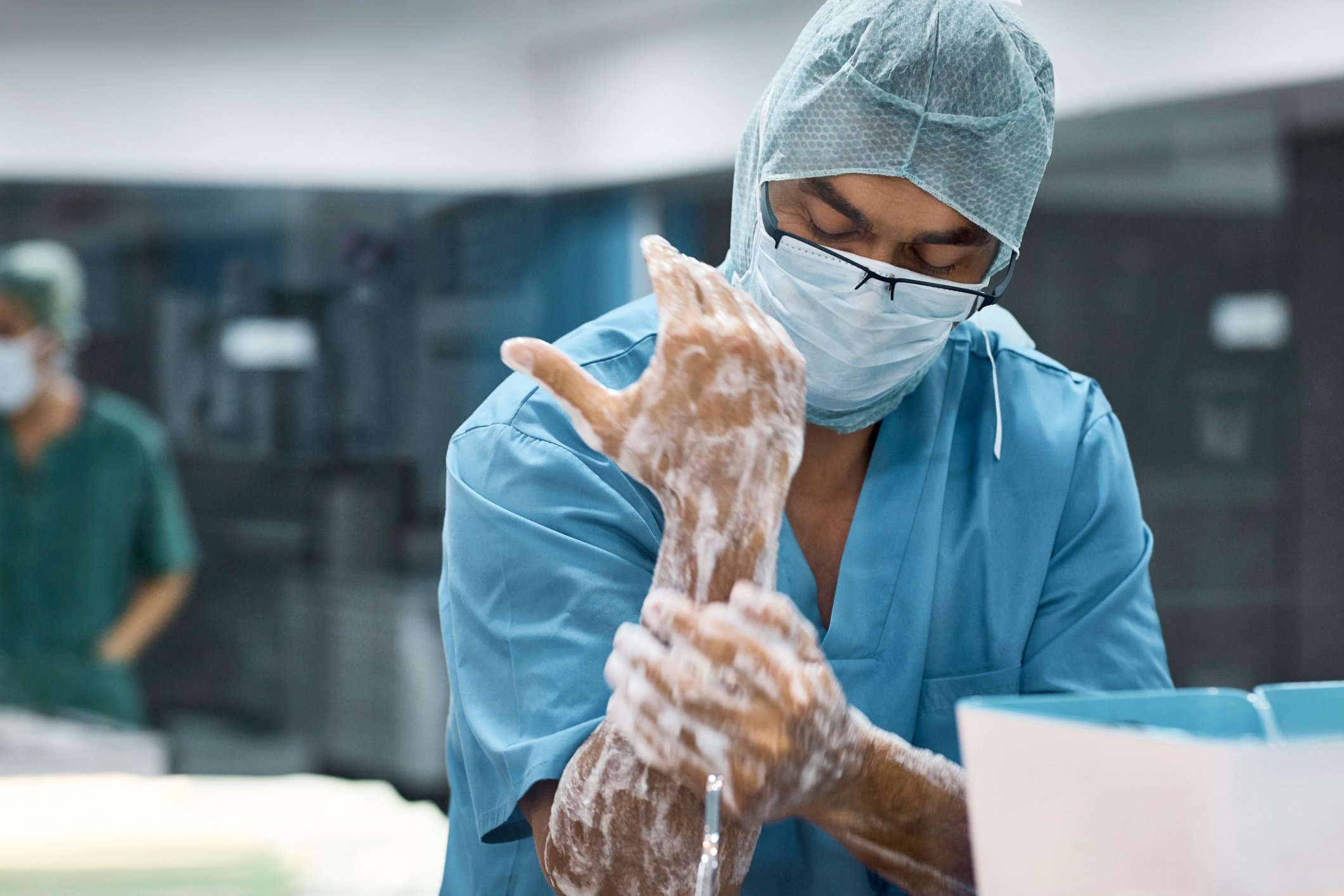 A surgeon scrubs down his hands while preparing to enter the operating room.