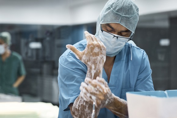 A surgeon scrubs down his hands while preparing to enter the operating room.