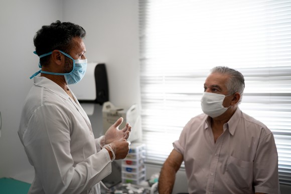 A patient sits in a treatment room with a physician. 