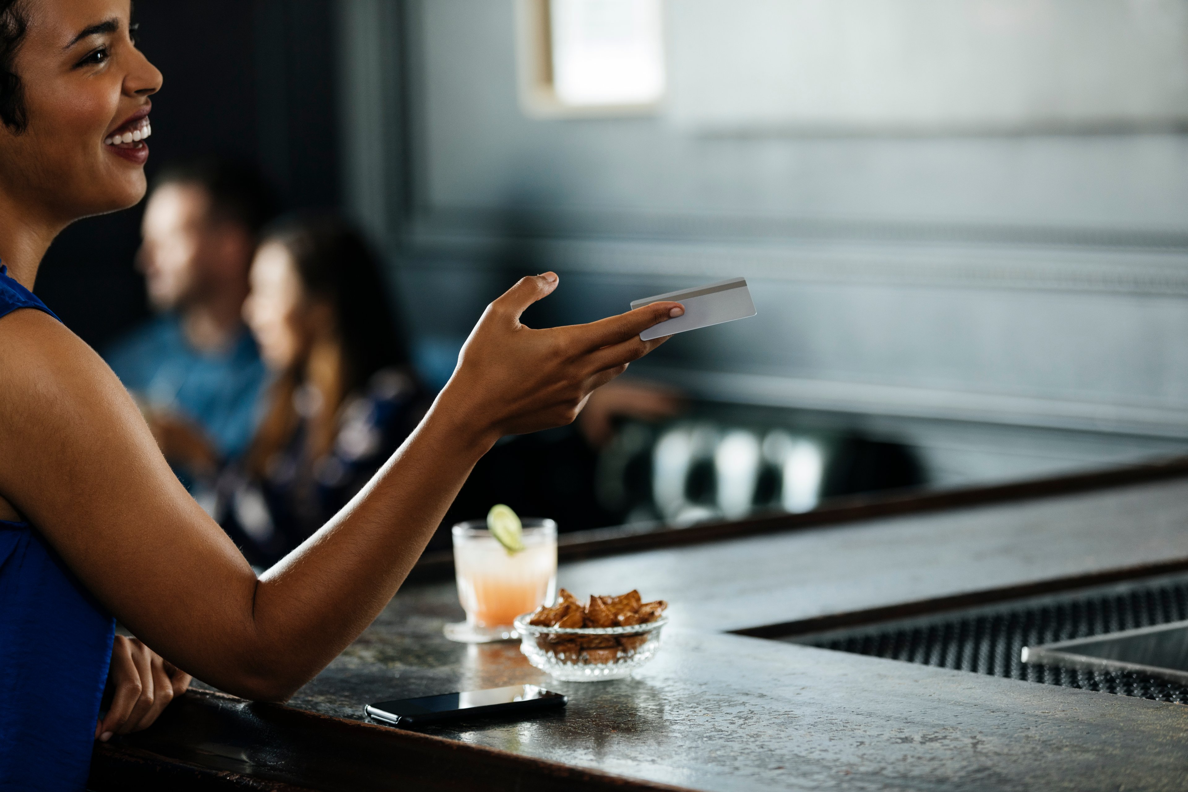 Woman handing her credit card to a bartender.