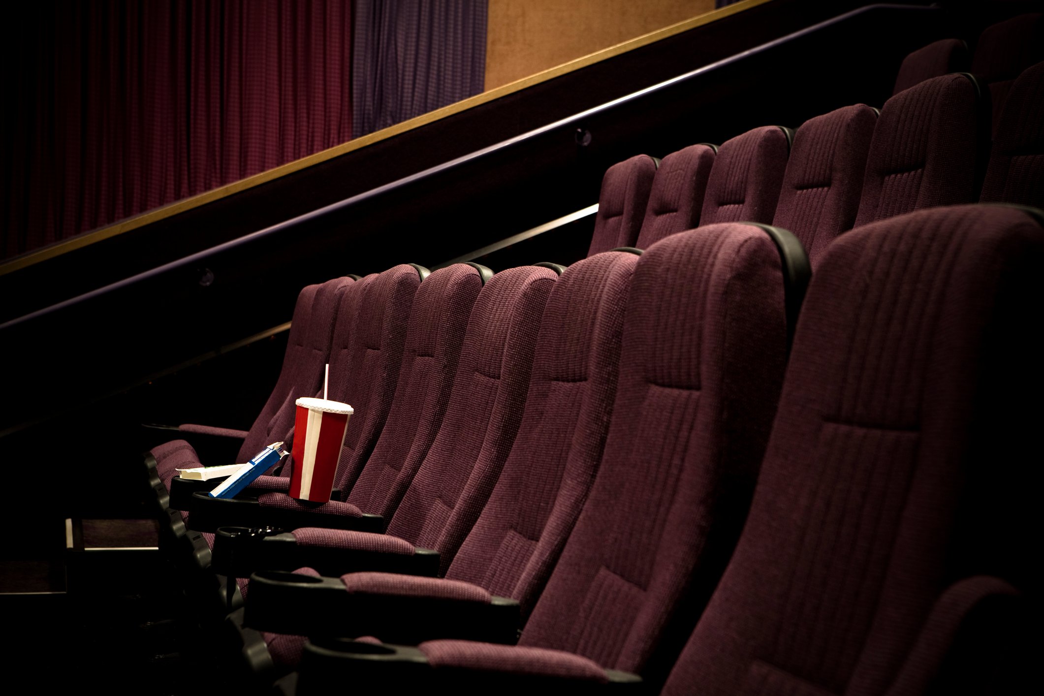 empty movie theater with soft drink sitting on seat.