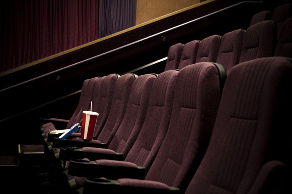 empty movie theater with soft drink sitting on seat.