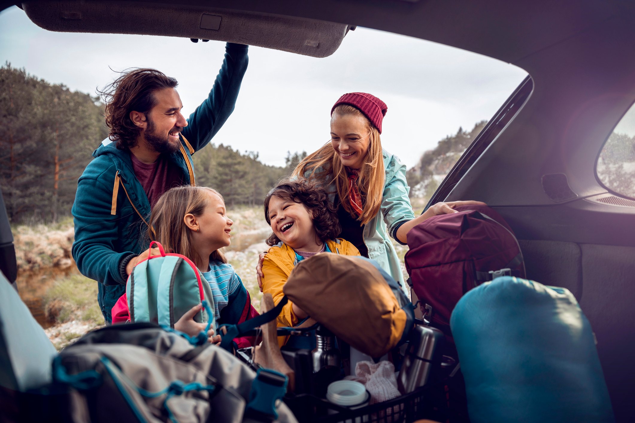Two adults and two children unpacking the trunk of a vehicle.