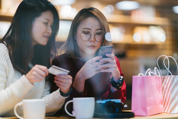 Two people using a mobile phone to shop.