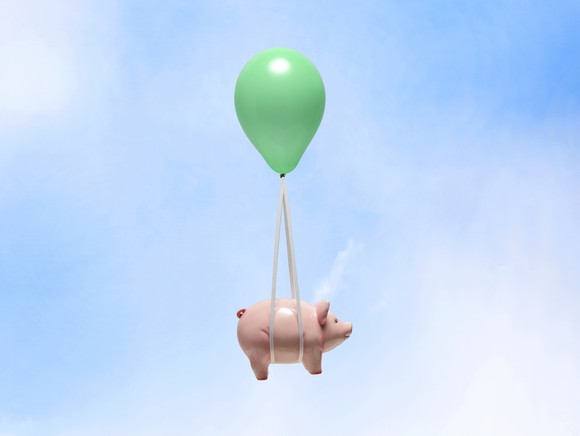 Pig attached to balloon flying through air.
