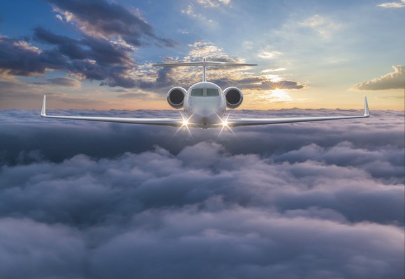 A private jet is flying over clouds. 