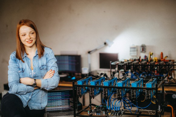 Person sitting next to a Bitcoin mining rig. 