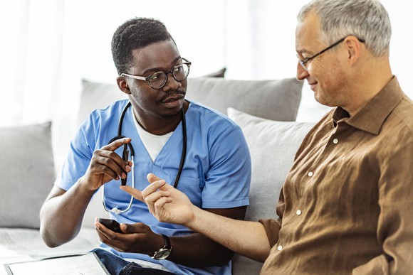 A caregiver helps a patient take a sample to check their blood sugar level.