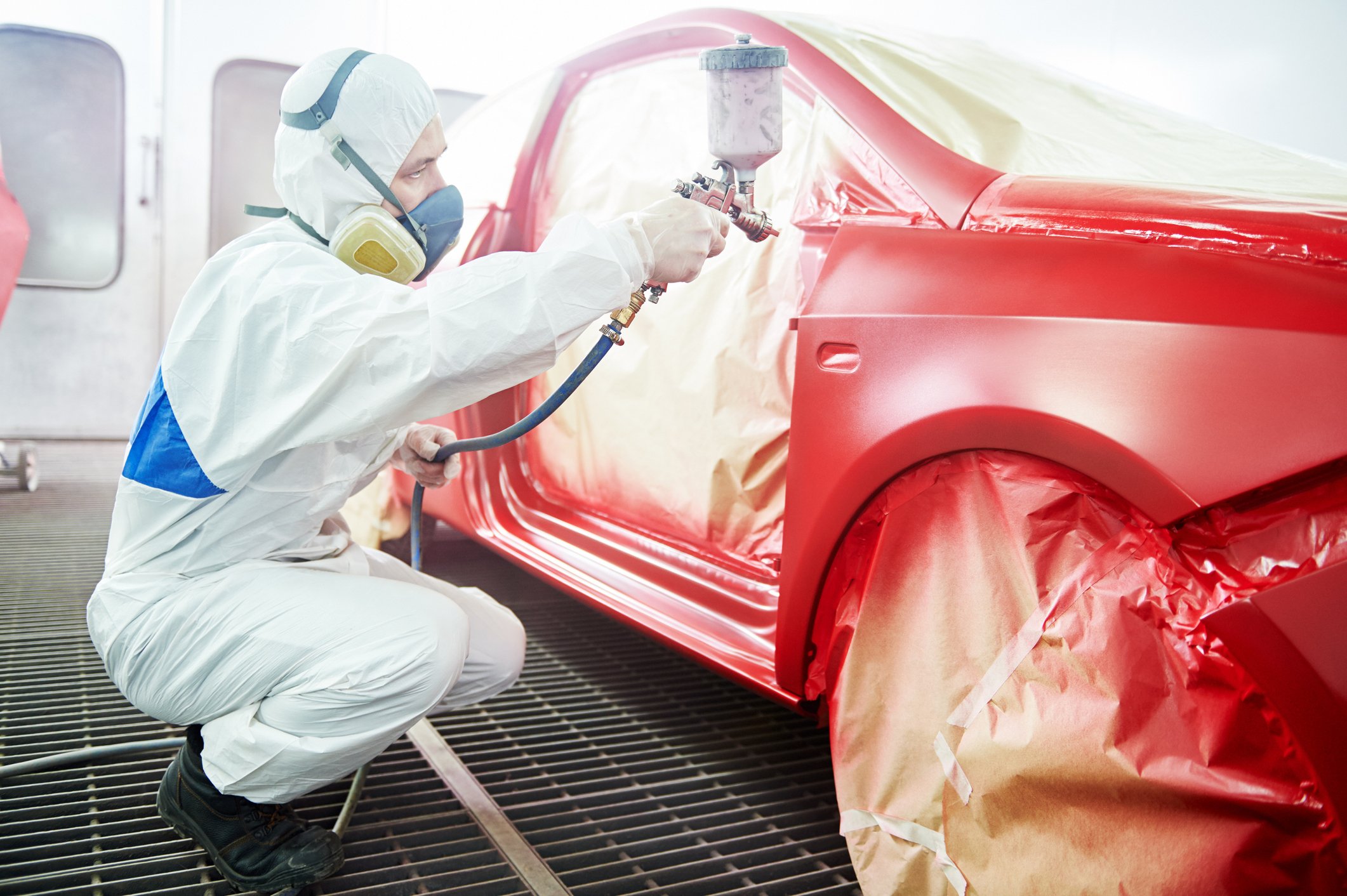A worker spray painting a car. 