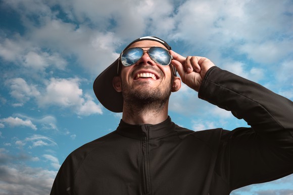 Person wearing sunglasses looking up at sky.