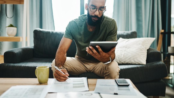 Man looking at tablet computer and financial sheets