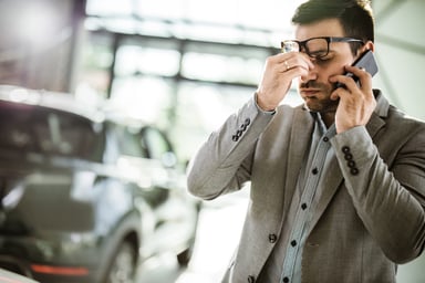 Car salesman has a headache in a car showroom