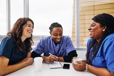 three nurses laugh at table