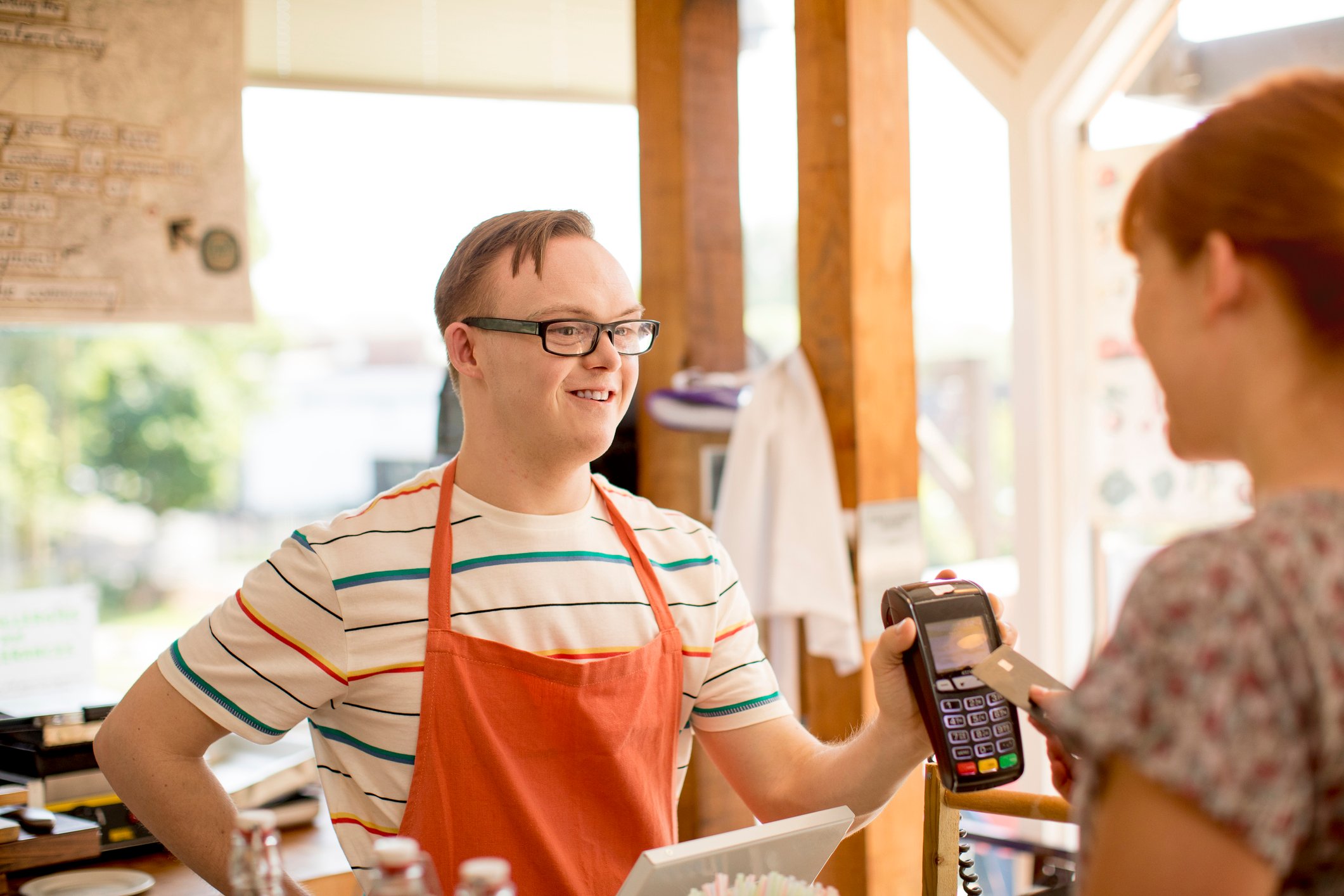 A cashier takes a customer's card payment with a card reader.