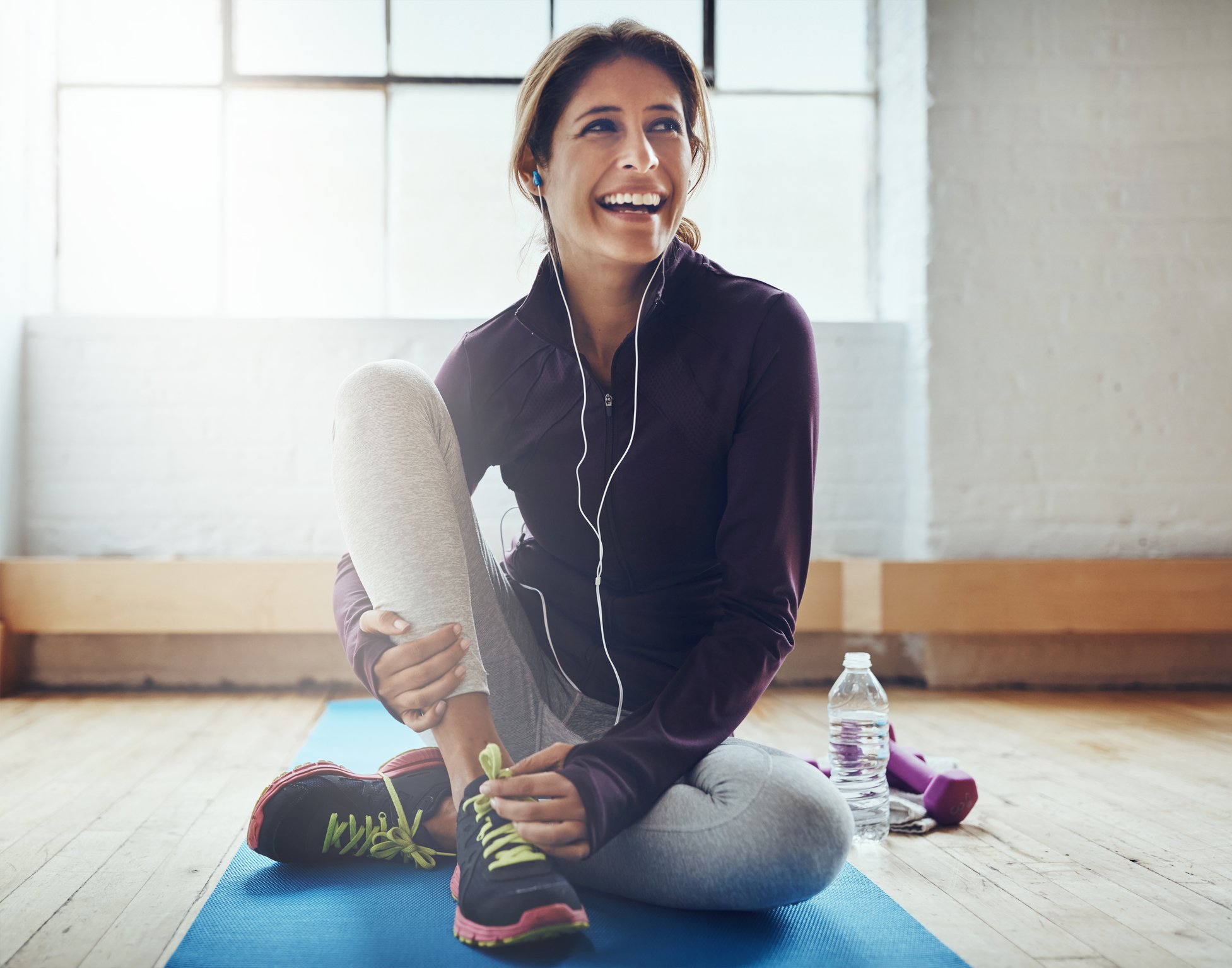 Person smiling and stretching on a yoga mat.