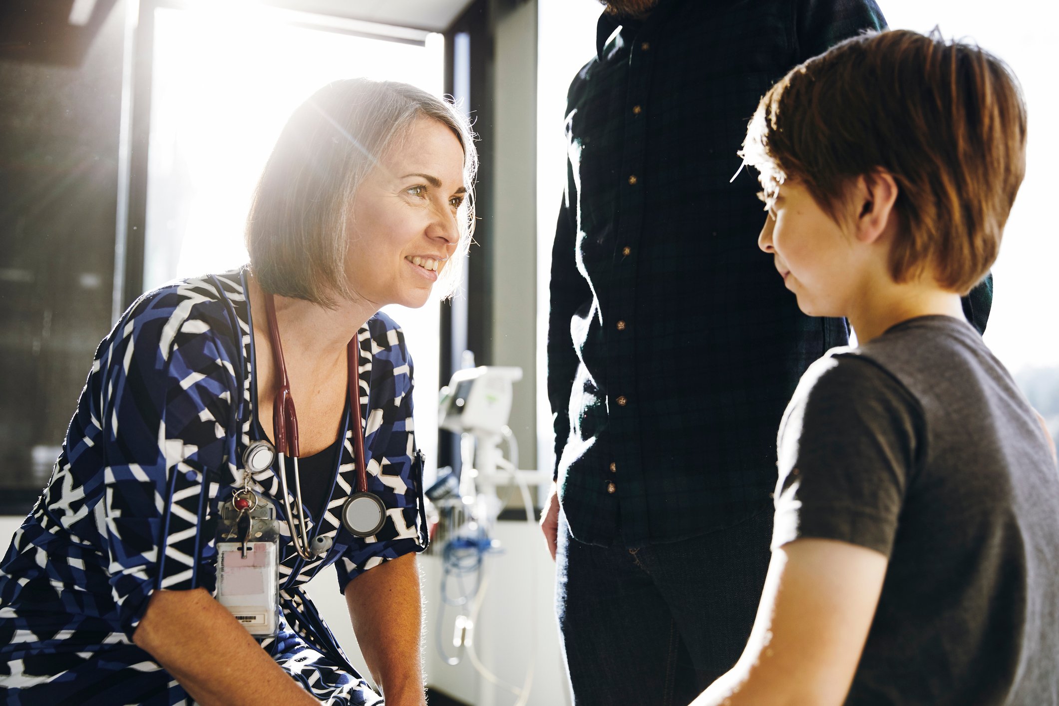 Smiling doctor talks to a young patient beside a parent in an office.