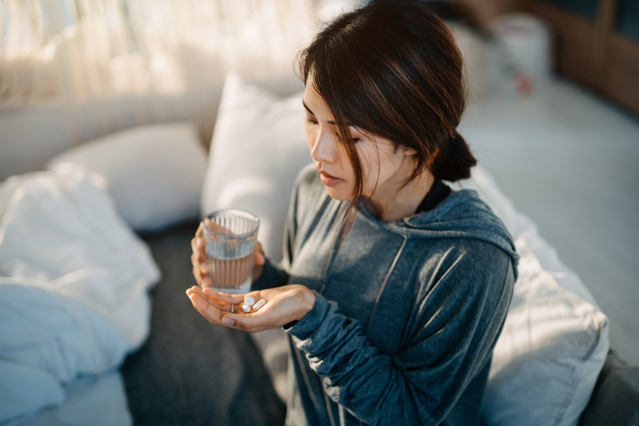 Woman takes two pills with a glass of water