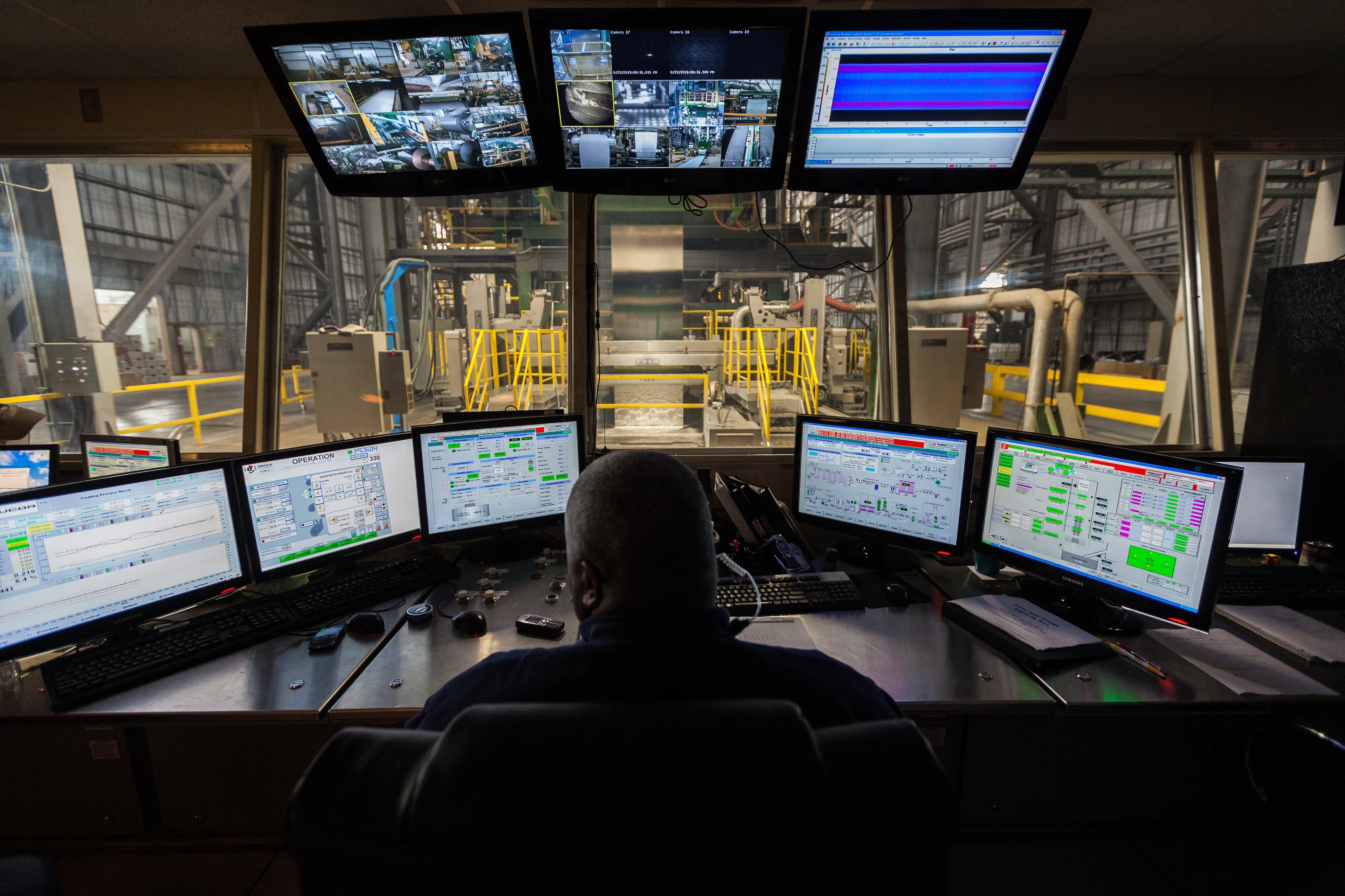 Nucor galvanizing line processing pulpit with computers and operator facing line.
