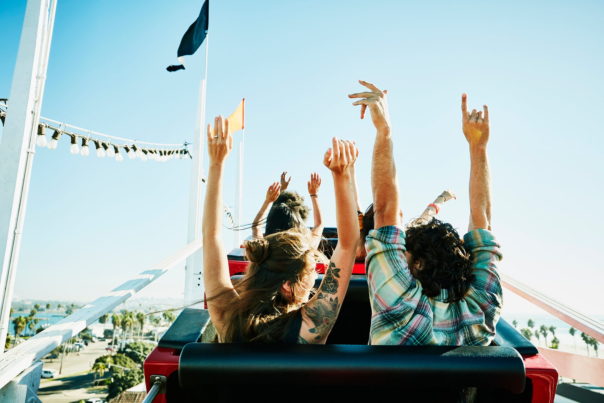 A group of people on a roller coaster going up a hill with their hands up in the air.