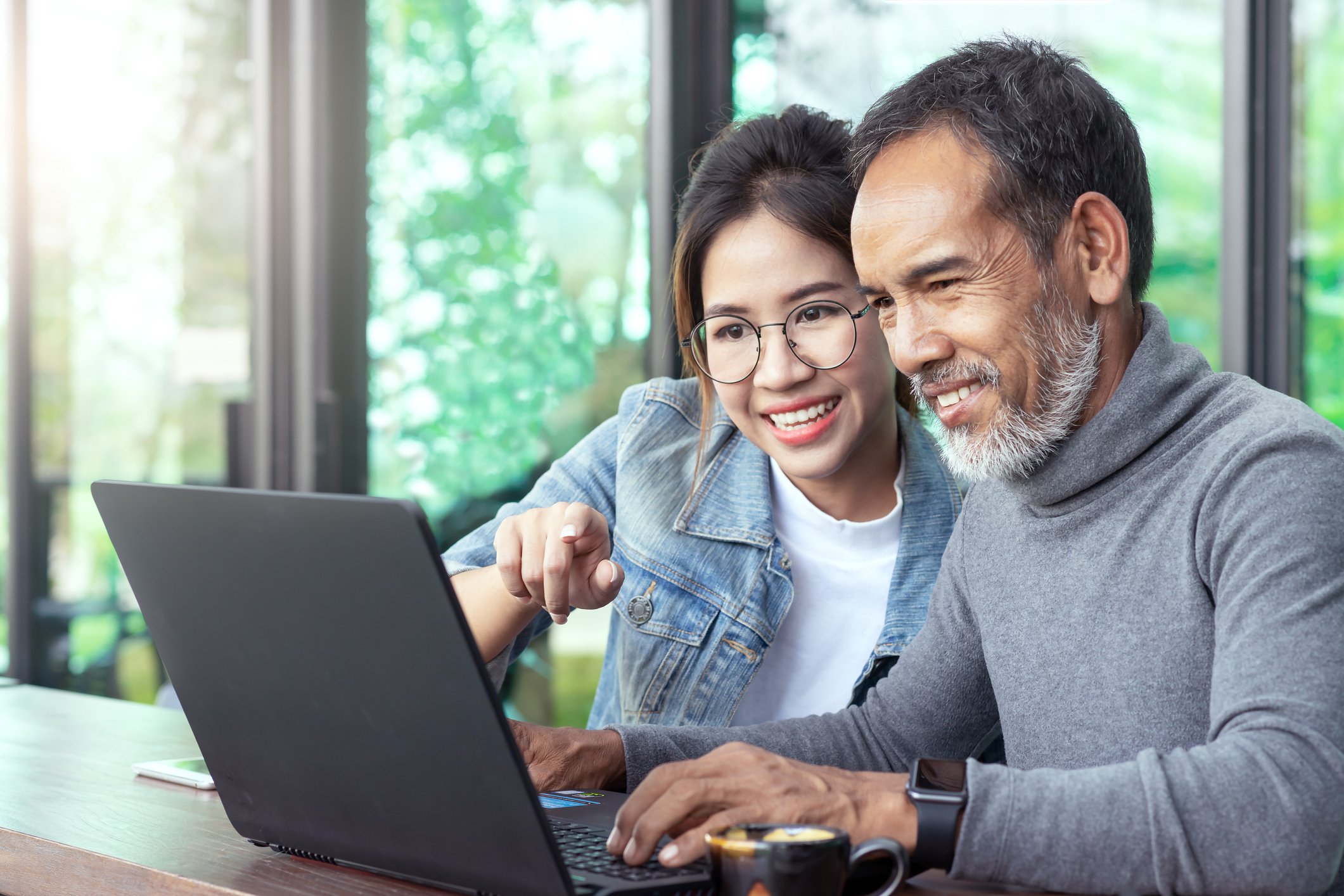Two smiling people looking at a laptop.