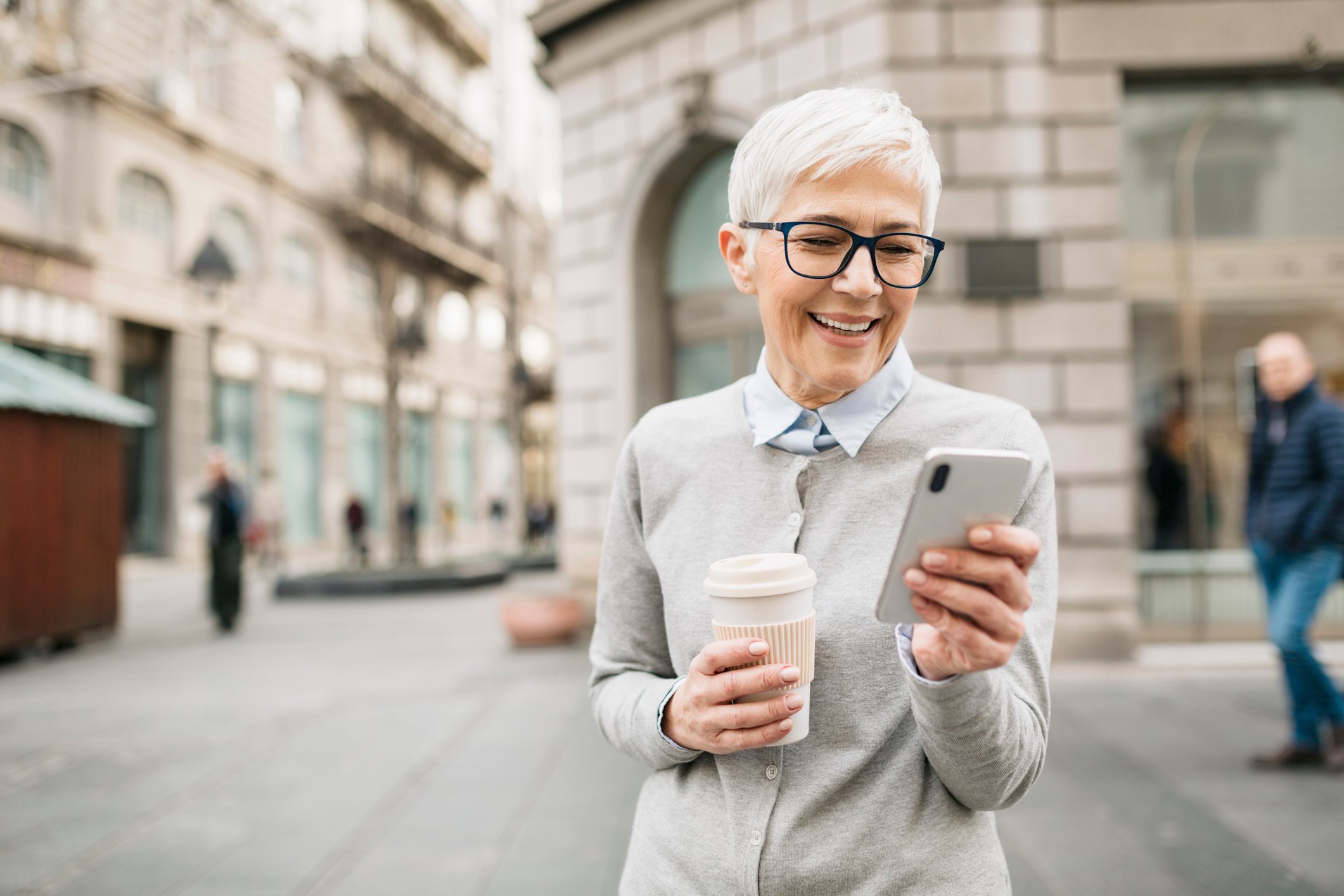 Person using their smartphone and drinking coffee.