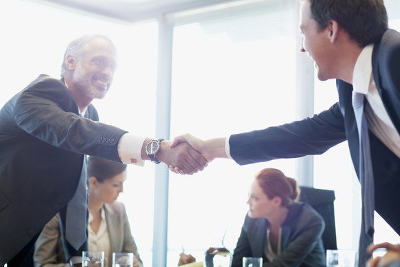 Businessmen shaking hands in a conference room.