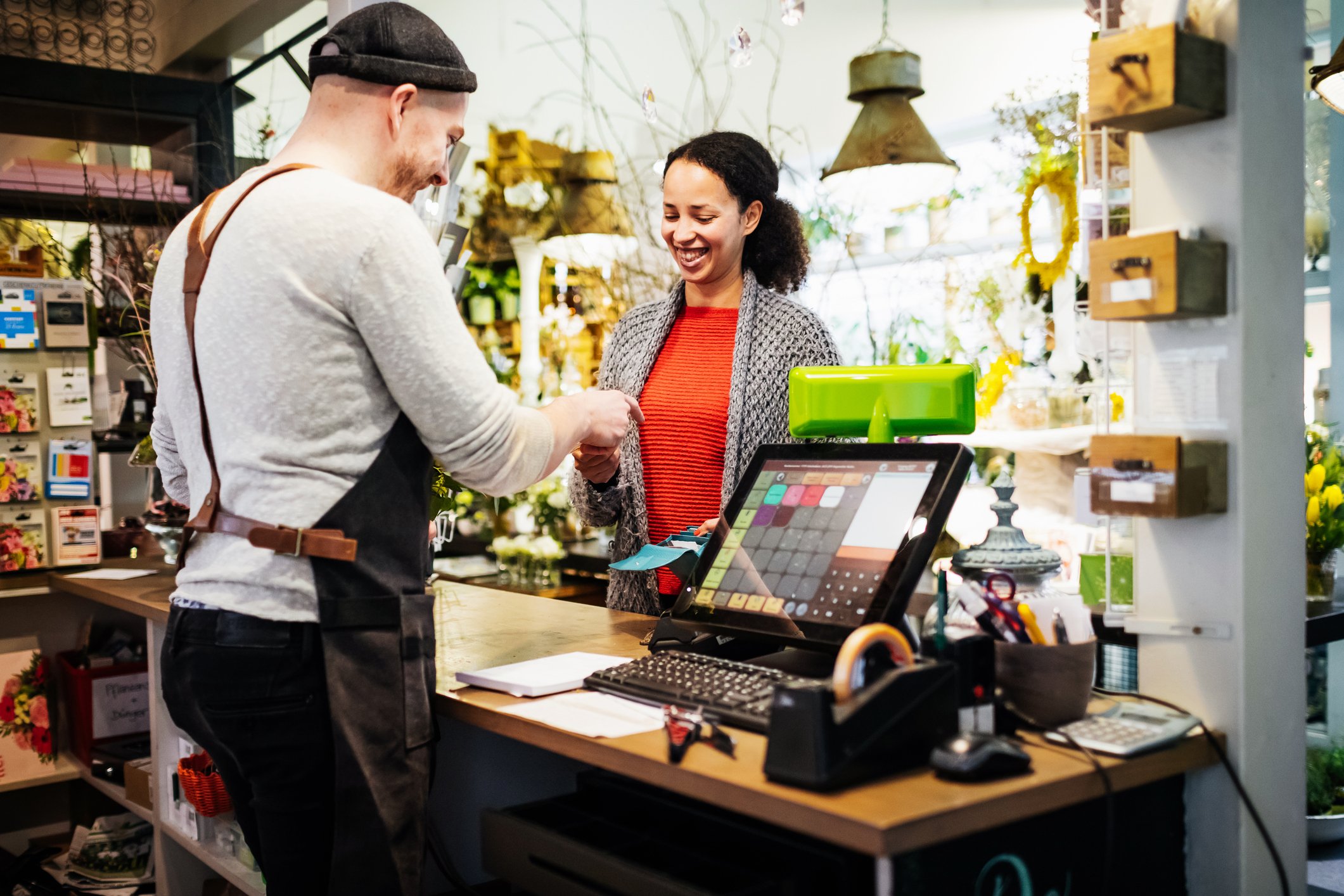 A woman paying in a store to a man behind a counter.