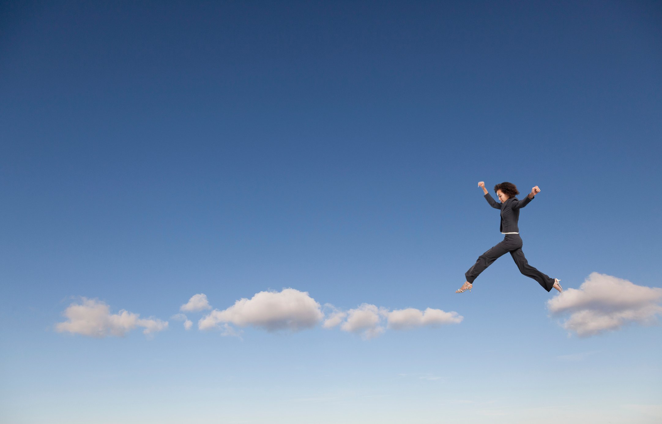 A woman hops from cloud to cloud in the sky. 