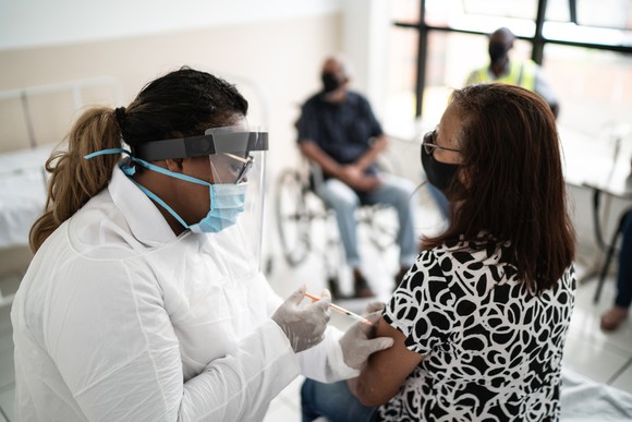 A person receives a shot in the arm from a healthcare worker.