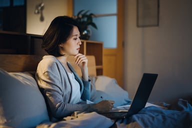 woman considers computer in bed