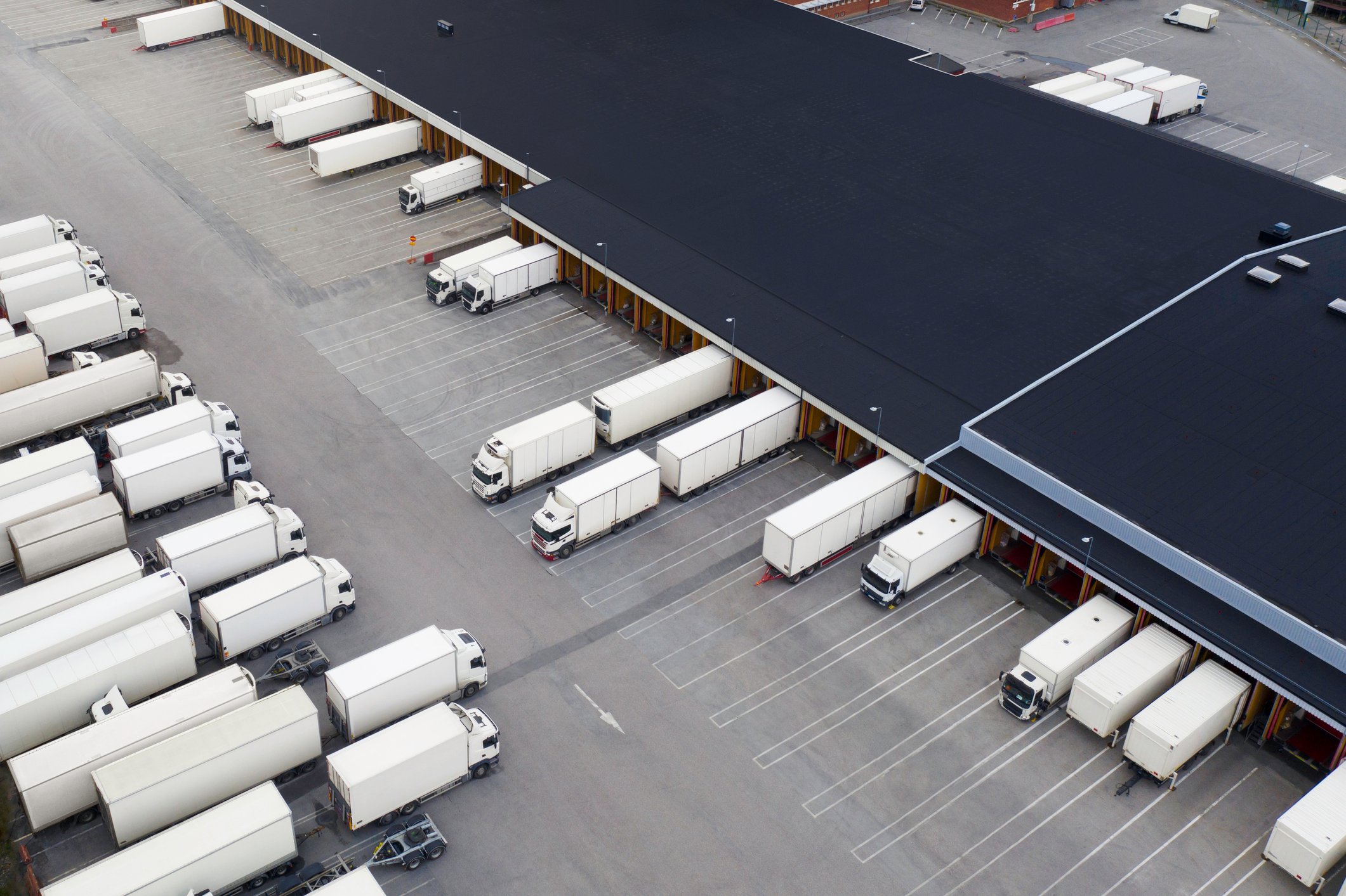 A fleet of freight trucks parked near a large warehouse