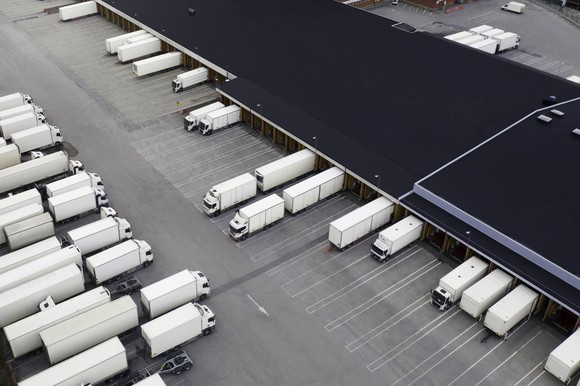 A fleet of freight trucks parked near a large warehouse