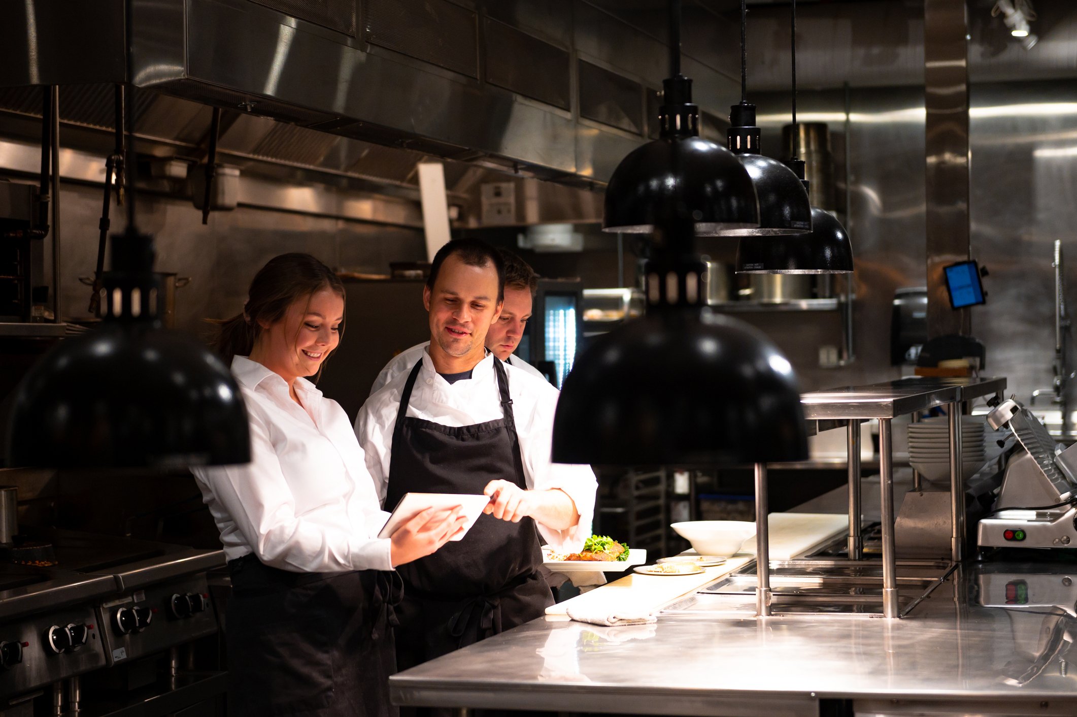 Three restaurant workers looking at a tablet.
