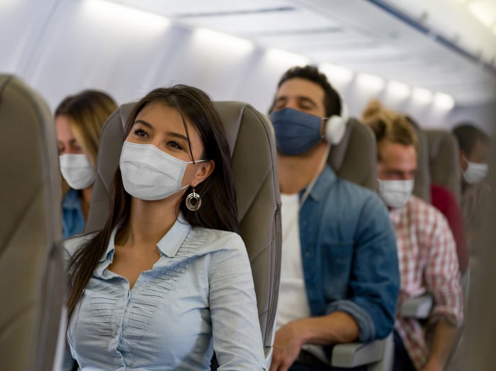 Airplane passengers seated while wearing masks.