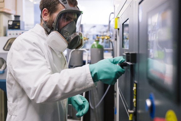 A worker in protective gear opening a chamber where 3D printing of metal is happening.