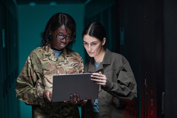 Two people wearing fatigues holding a laptop.