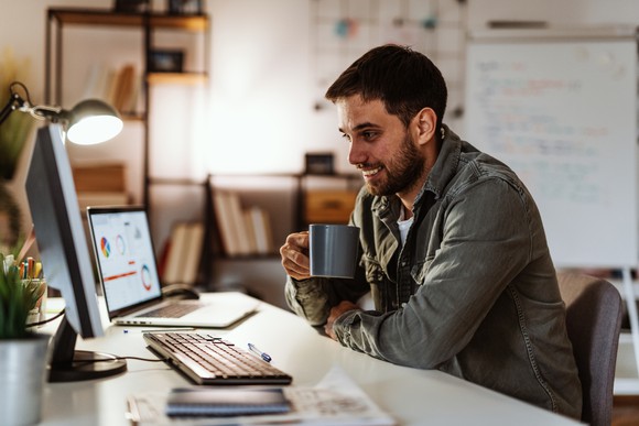 Person viewing finances on computer screens in home office. 