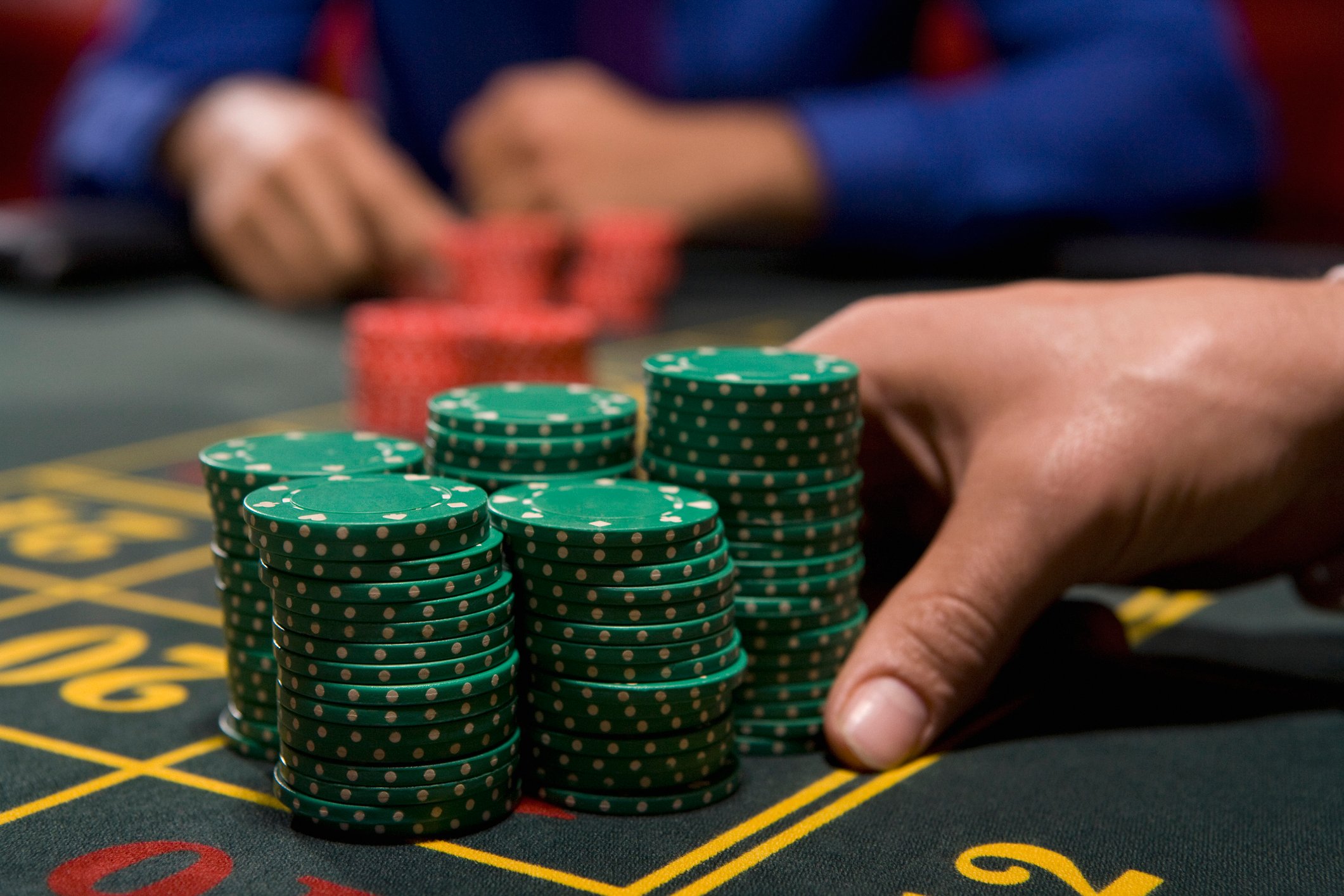 Closeup on gamblers hands moving a stack of chips onto a roulette table. 