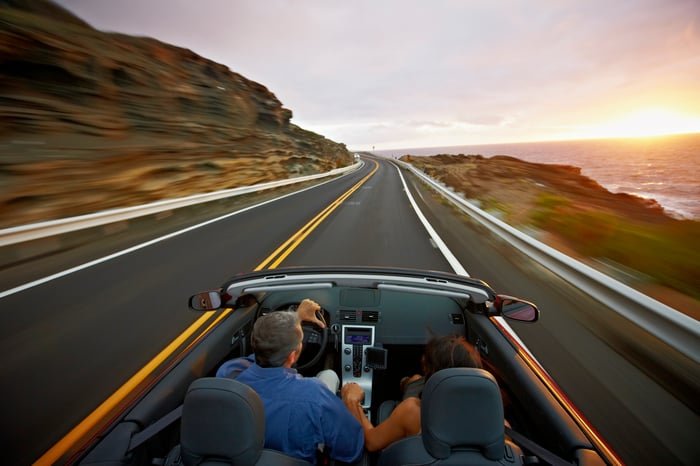 A couple drive in a convertible at sunrise.