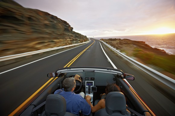 A couple drive in a convertible at sunrise.