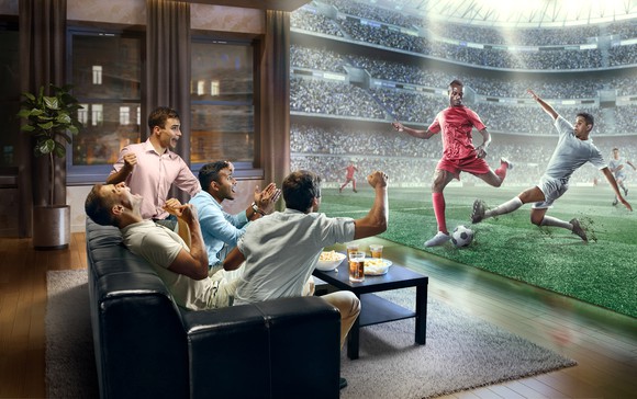 Friends watching a soccer game at home on a large TV. 