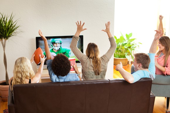 A group of people watching a game on television and cheering.