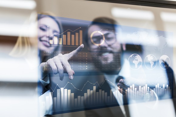 Two people looking at charts on a screen.
