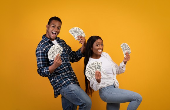 A man and a woman holding fanned out cash.