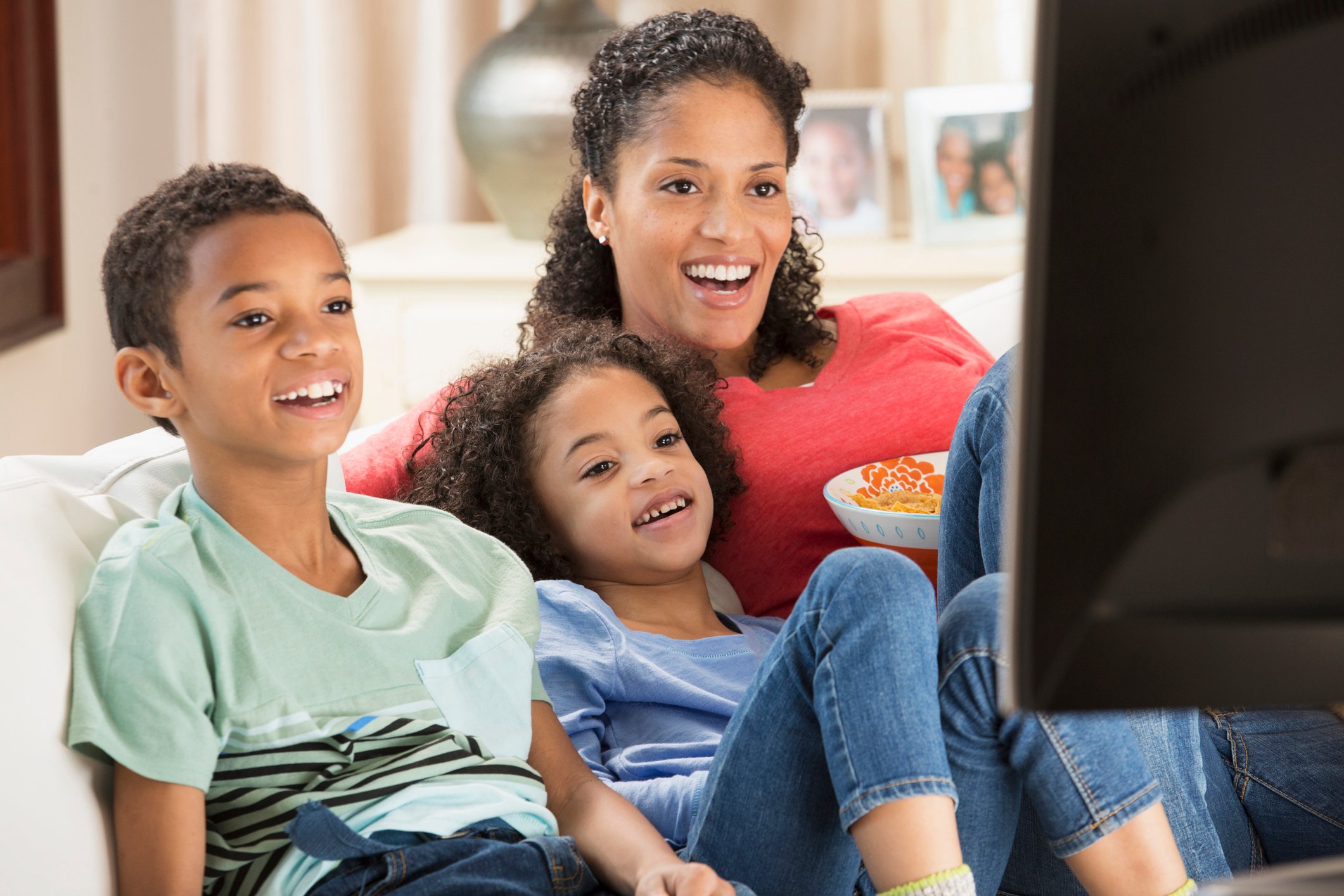 Adult and children watching TV from their couch.