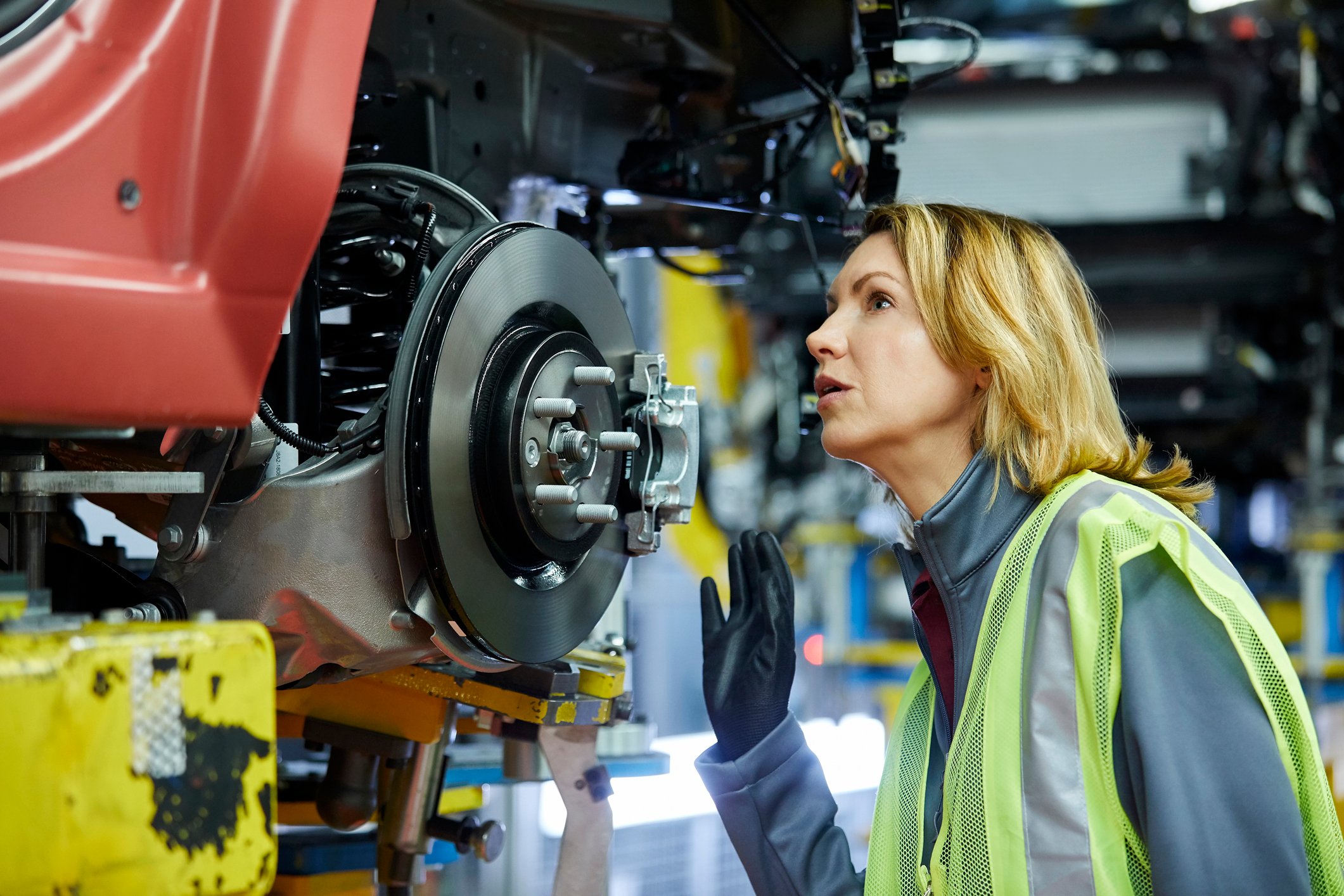 Worker inspecting a vehicle in a manufacturing plant.