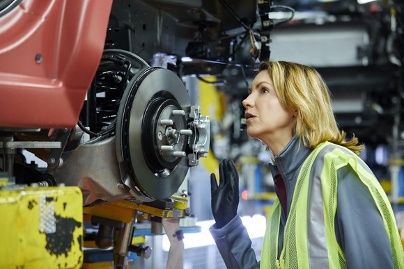 Worker inspecting a vehicle in a manufacturing plant.