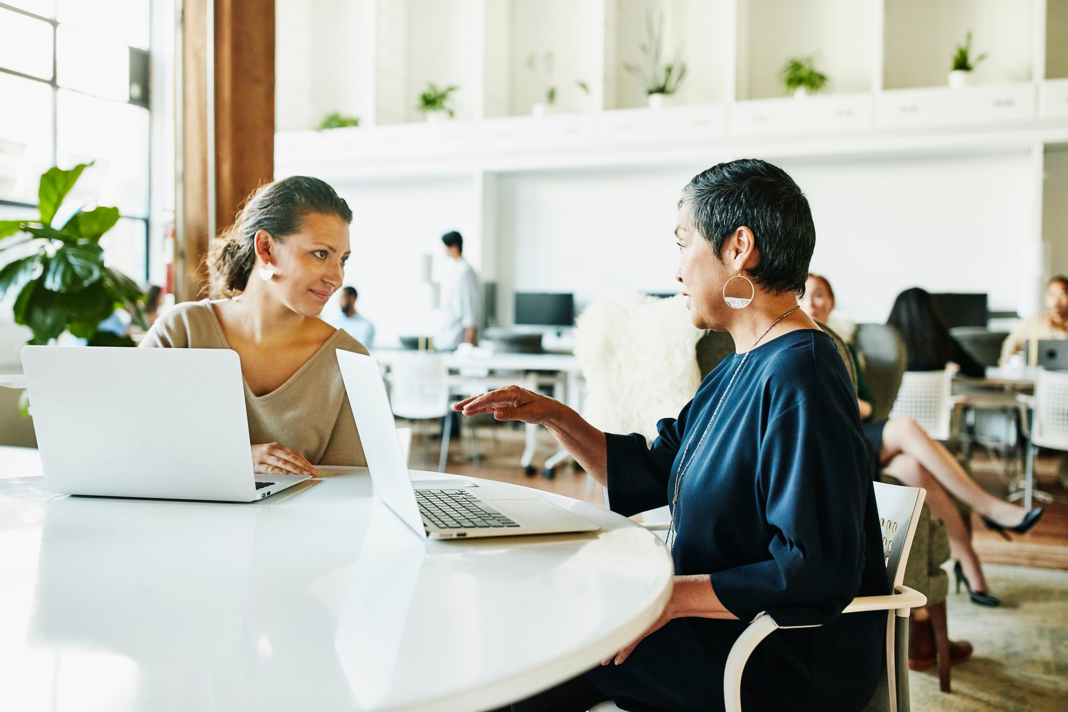 Two people at table with laptops.